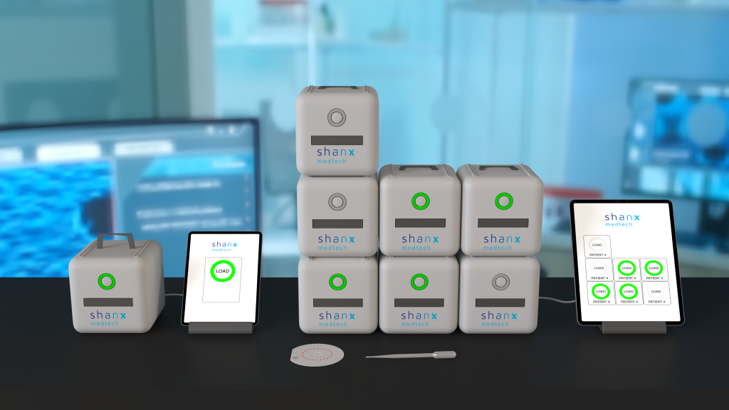 A mockup of ShanX Medtech's Antibiotic Susceptibility testing devices stacked on top of each other. The boxes are connected wirelessly to a tablet which monitors their progress. On the black table, you find a circular cassette-type dish and a separate dropper.